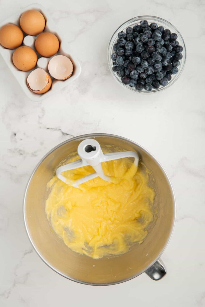 Butter, sugar, and eggs mixed together in a stainless steel mixing bowl.