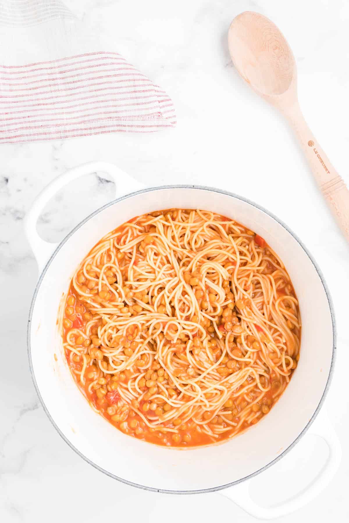 Pasta, creamy tomato sauce, and lentils in a white pot.