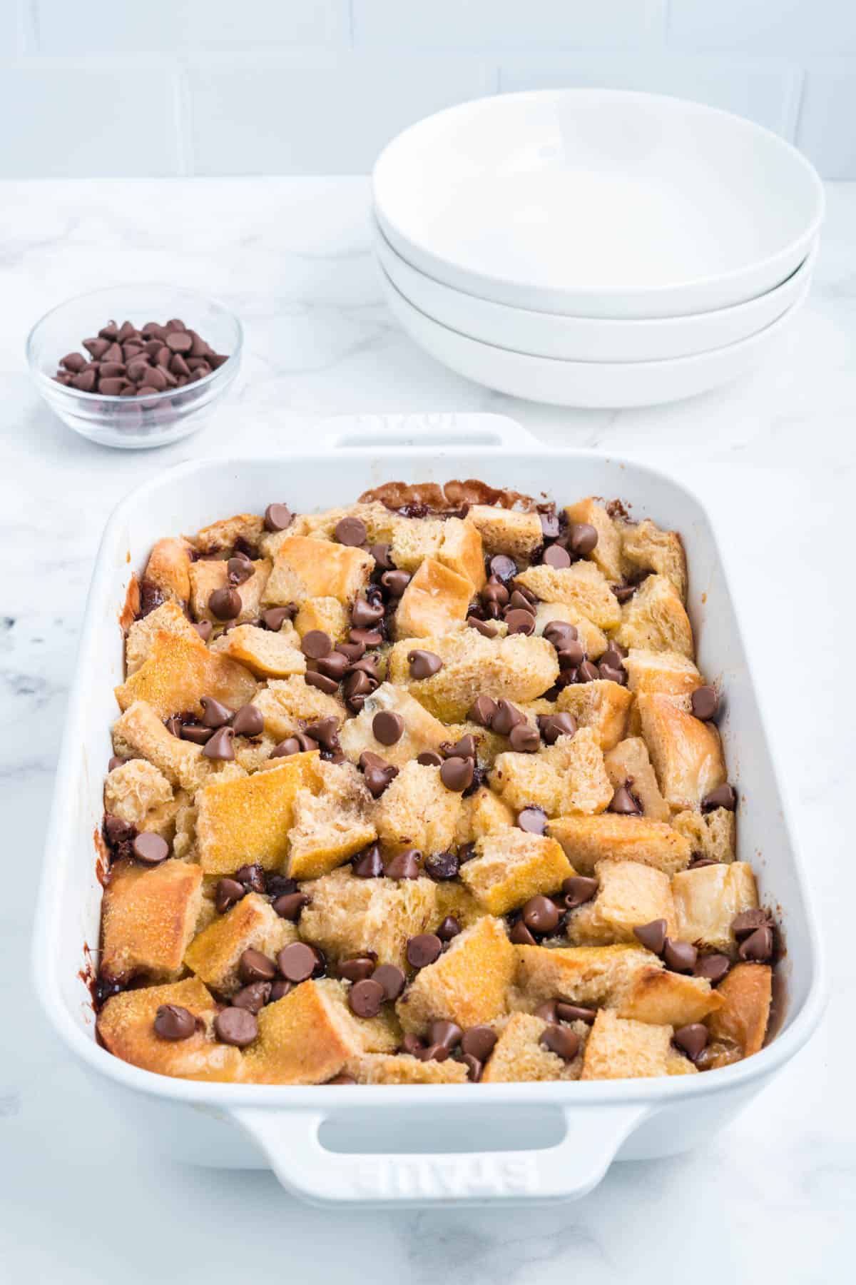 Choc chip bread pudding in a white baking dish.