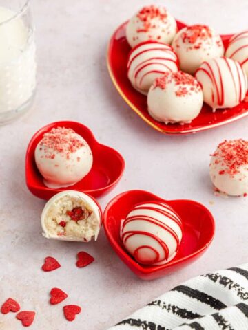 Strawberry cheesecake cake pops (cake balls) in small heart-shaped dishes.