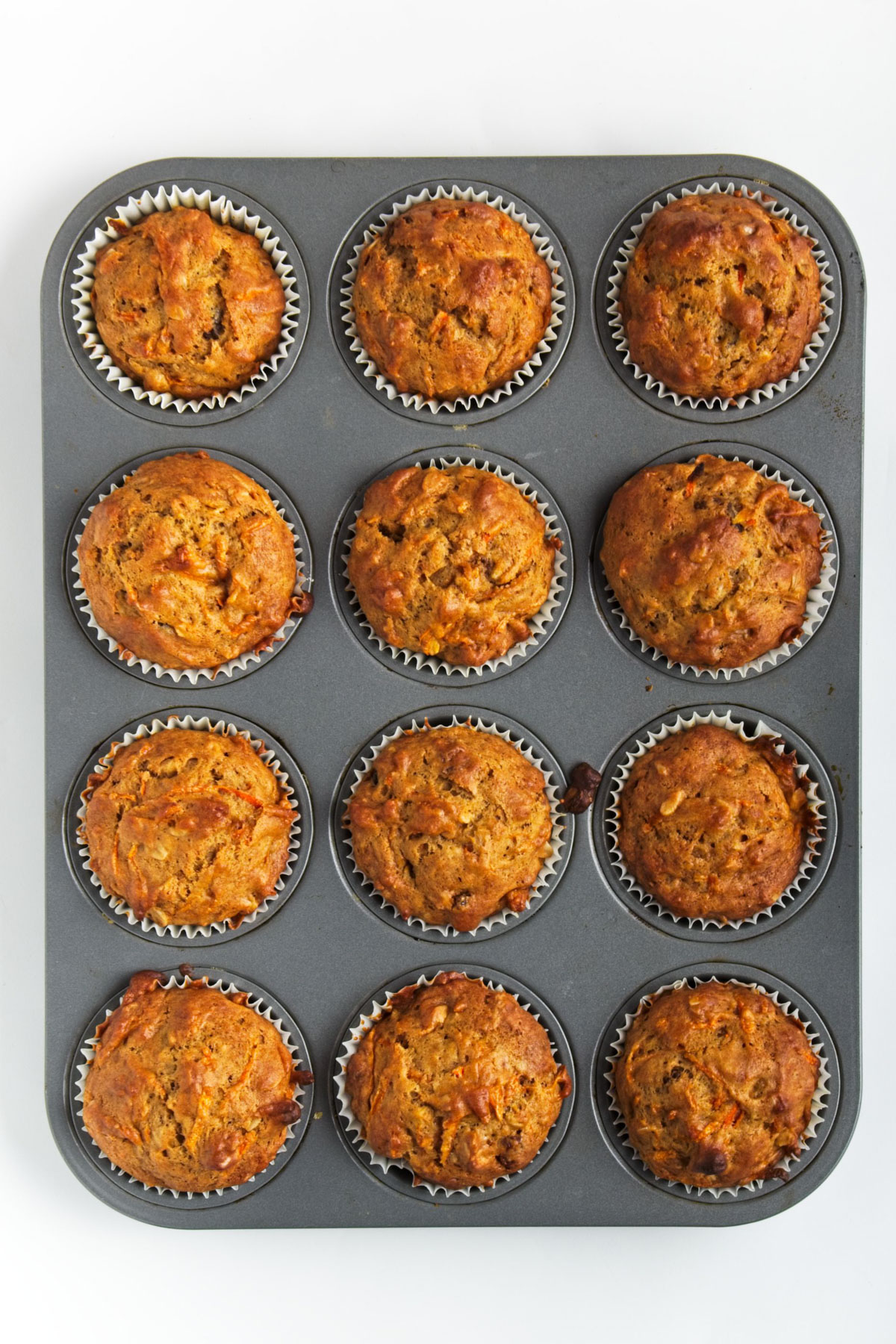 Cooked oatmeal carrot muffins in a muffin tin.