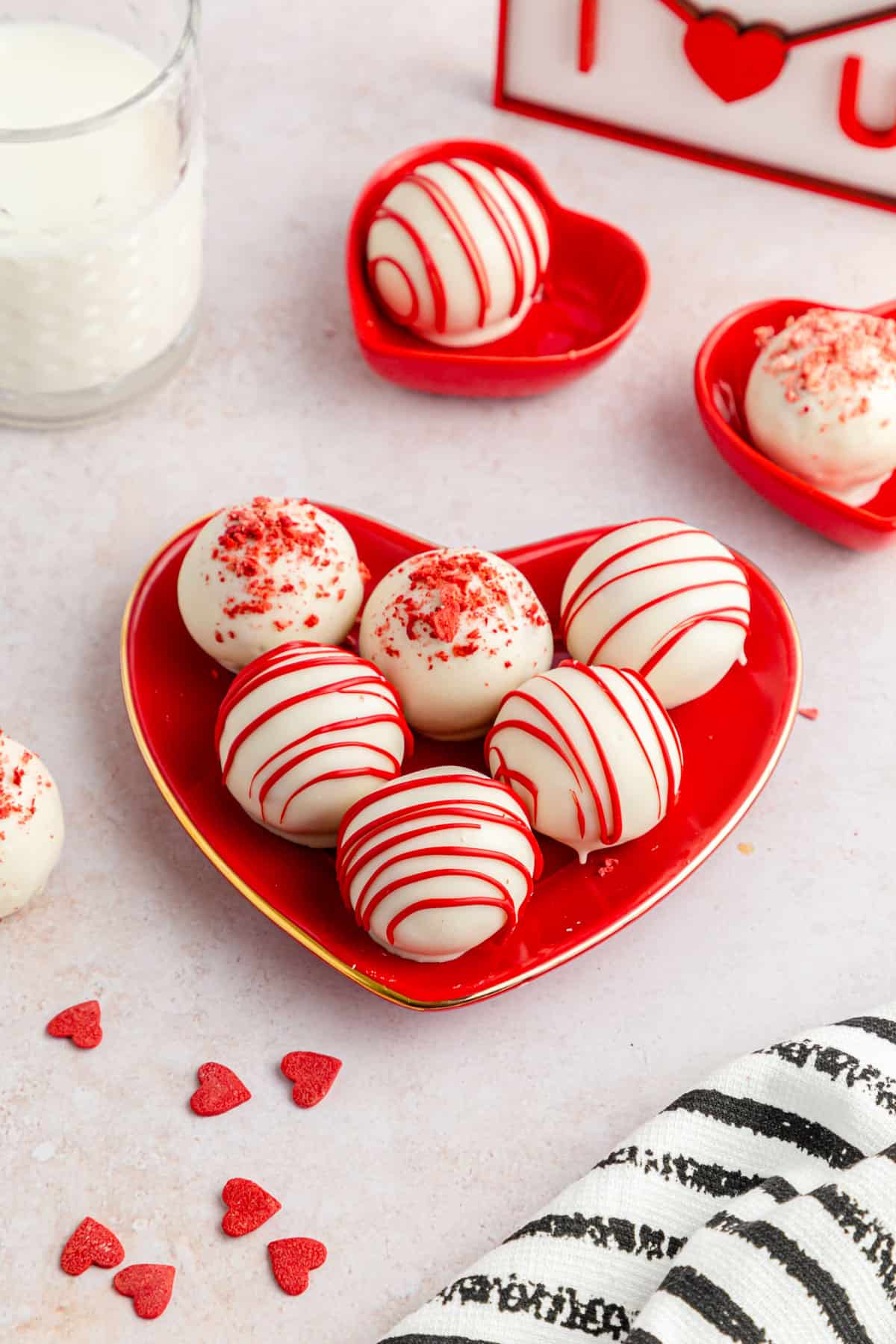 White and red strawberry cake balls (cake pops) on a red heart plate.