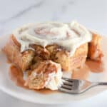 A single TikTok cinnamon roll on a white plate with a fork.