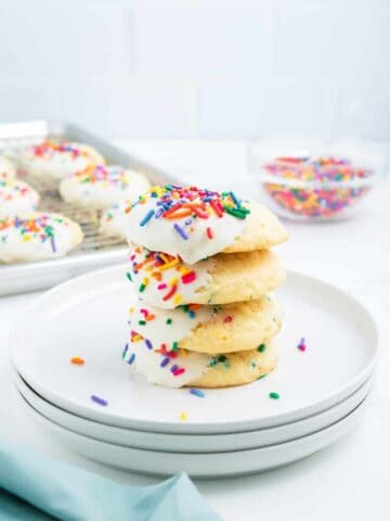 A stack of funfetti cake mix cookies on white plates.