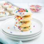A stack of funfetti cake mix cookies with frosting and rainbow sprinkles.