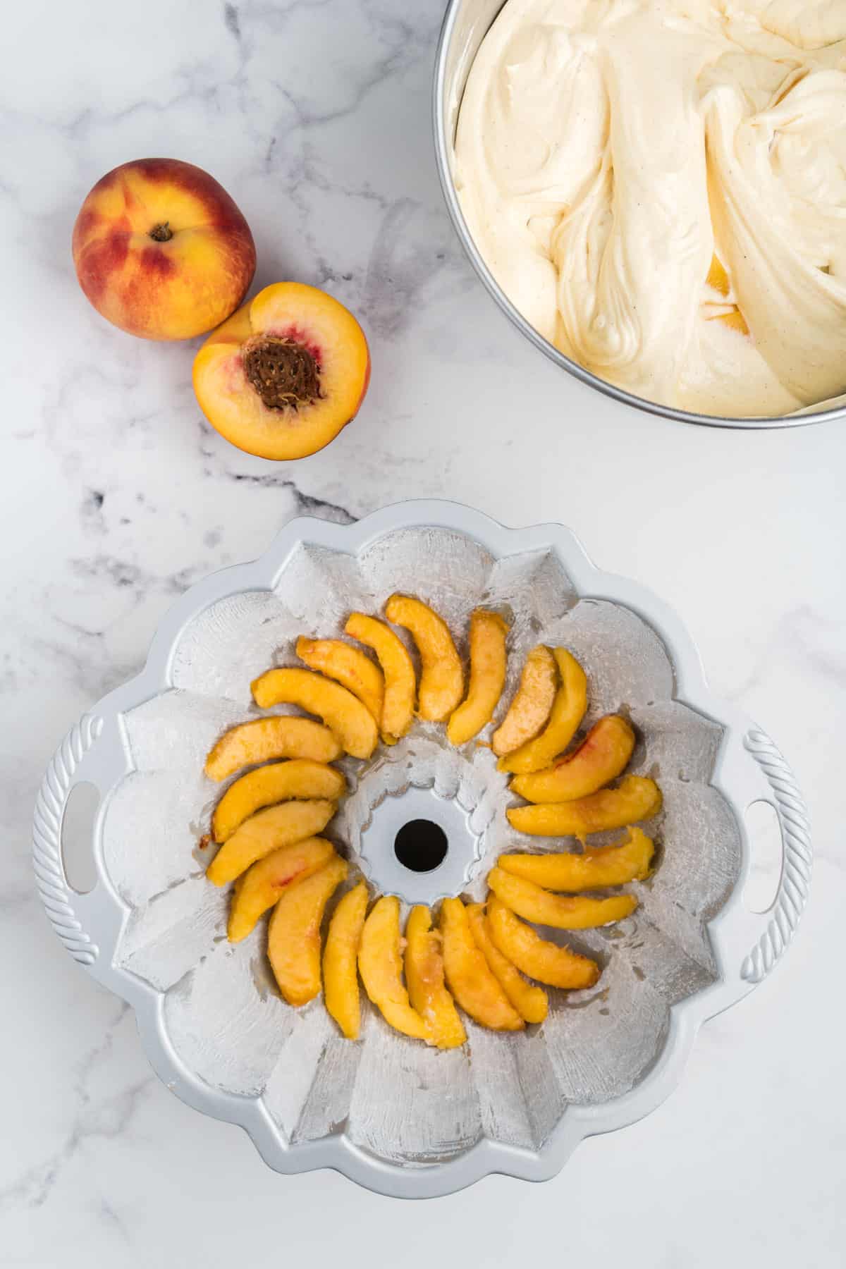 Fresh peach slices layered inside of a greased bundt pan.