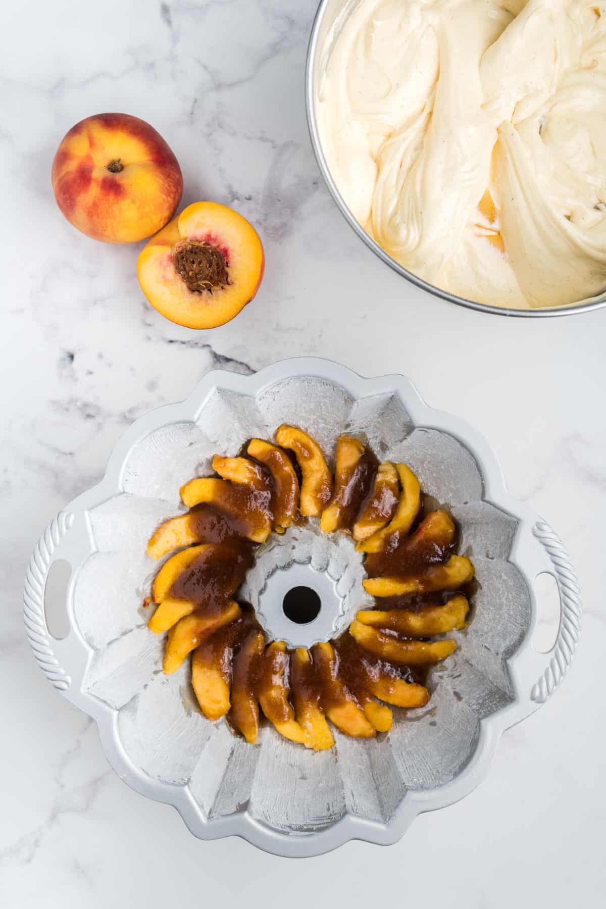 Peaches layered in the bottom of a bundt pan with brown sugar and butter mixture on top.
