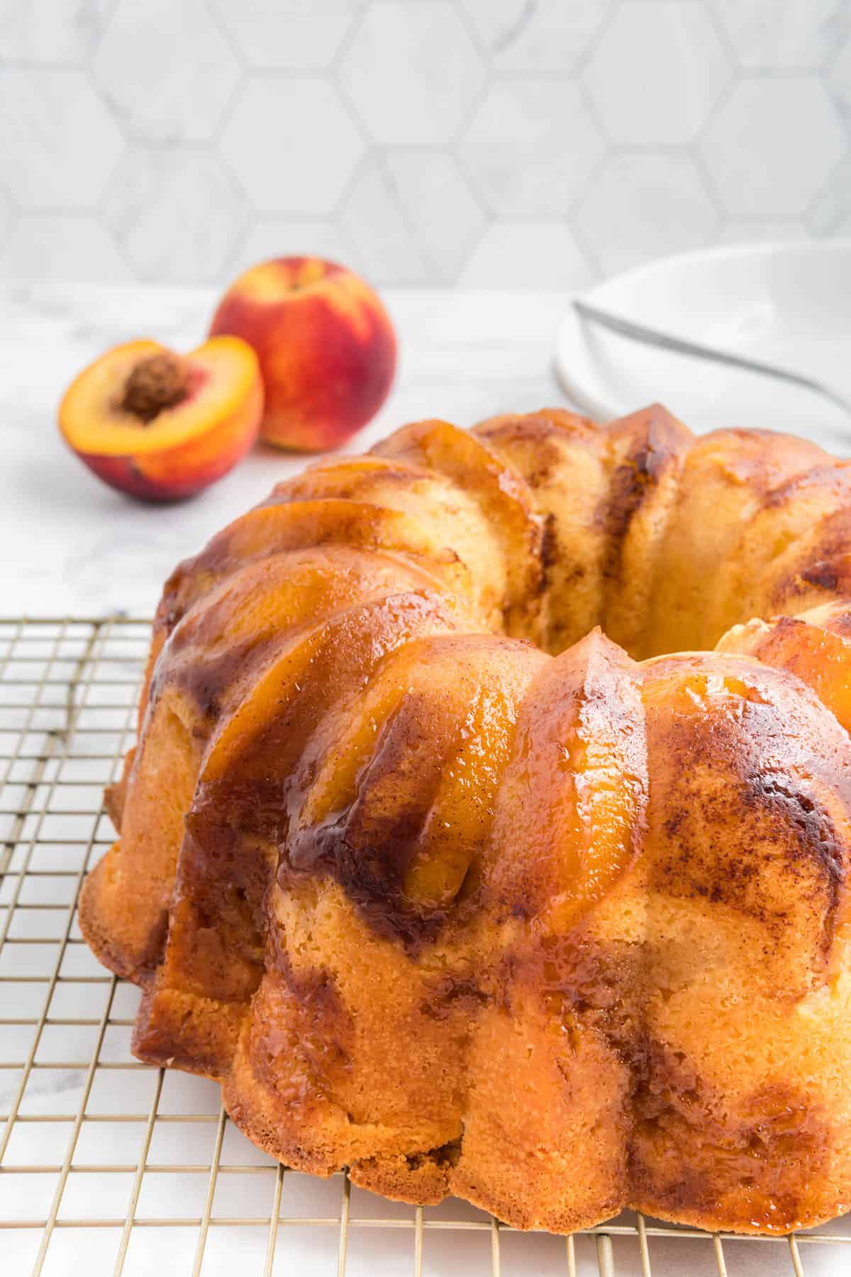 Peach cobbler bundt cake made with cream cheese on a wire cooling rack.