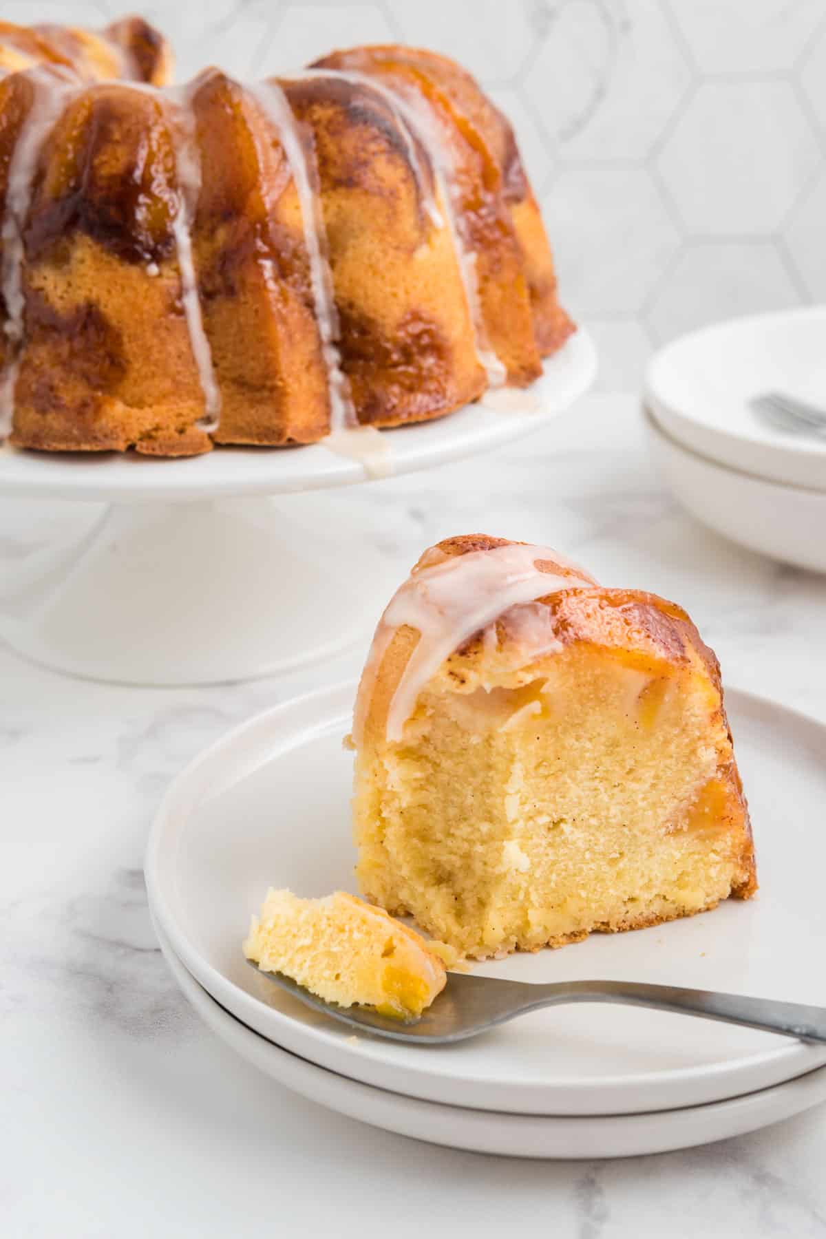 A slice of peach cobbler pound cake on a stack of white plates.
