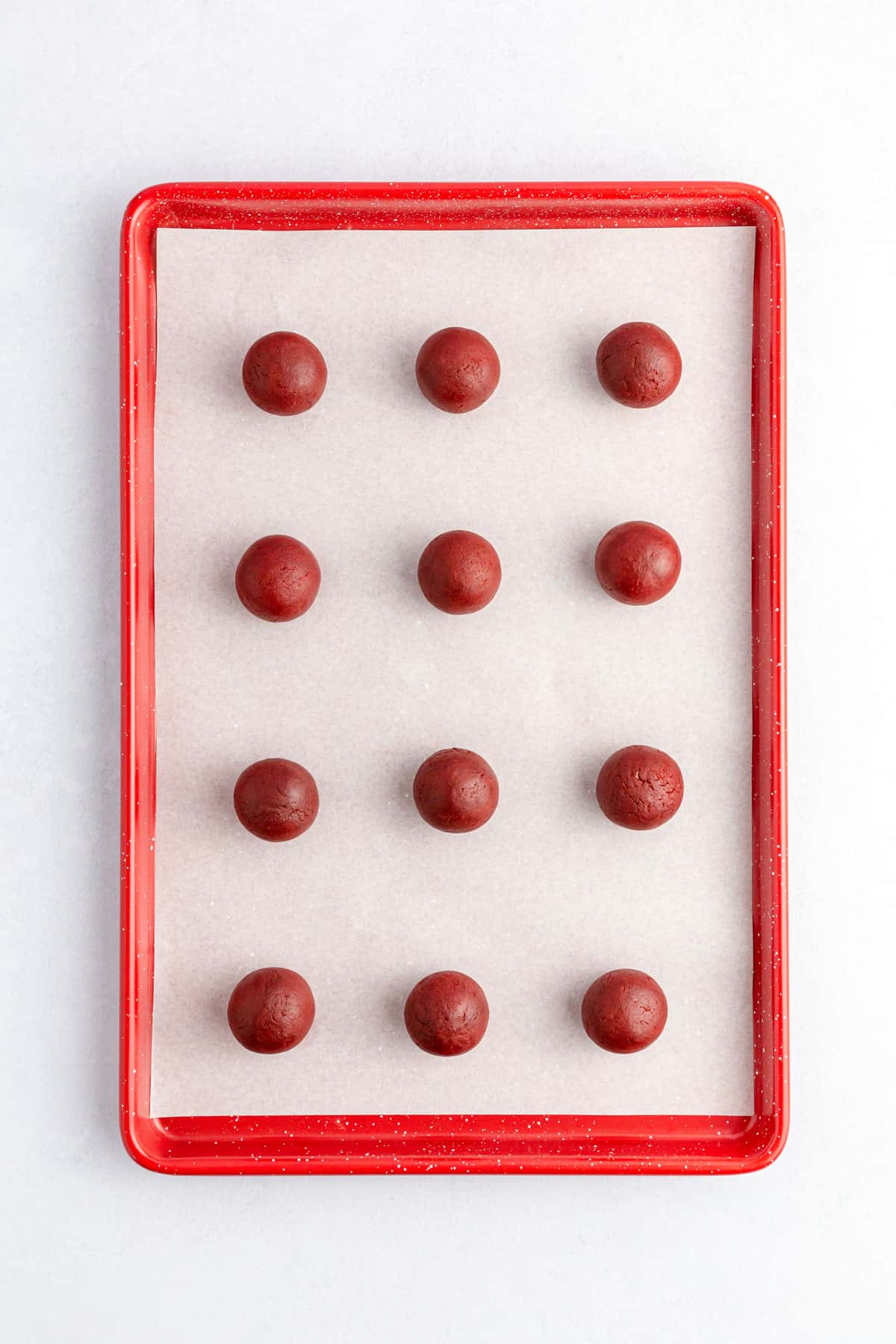 Red velvet cake dough balls on a baking tray.