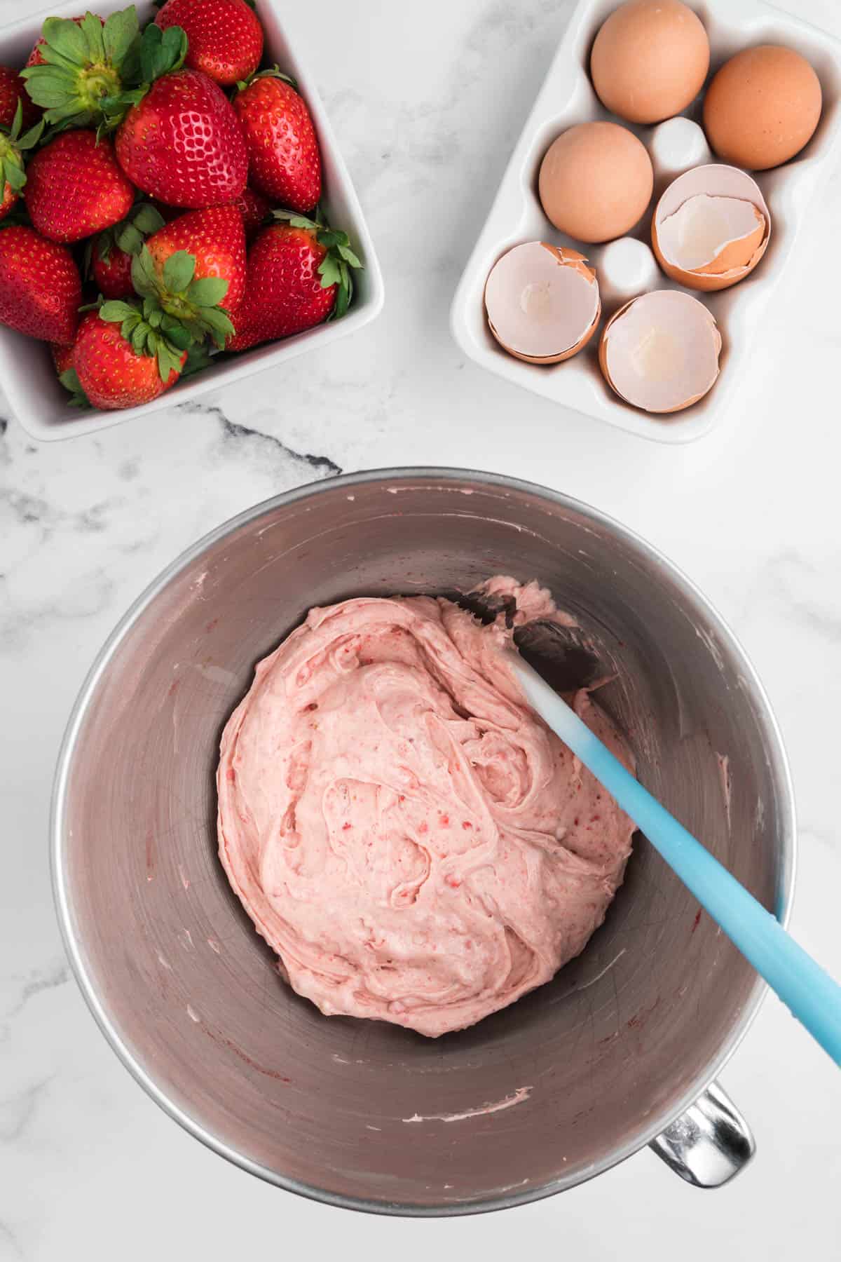 Strawberry cream cheese frosting in a stainless steel mixing bowl.