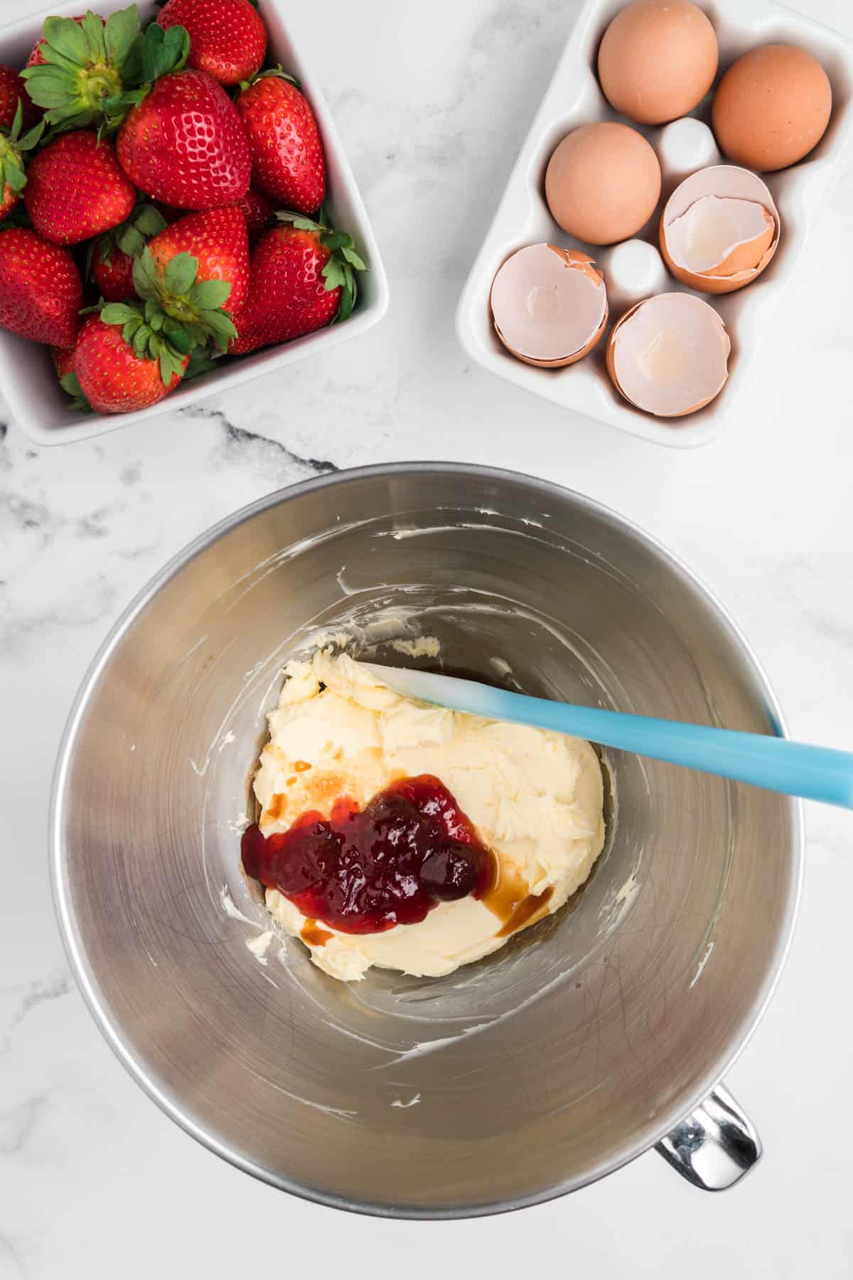 Cream cheese with strawberry preserver and vanilla in a stainless steel bowl.