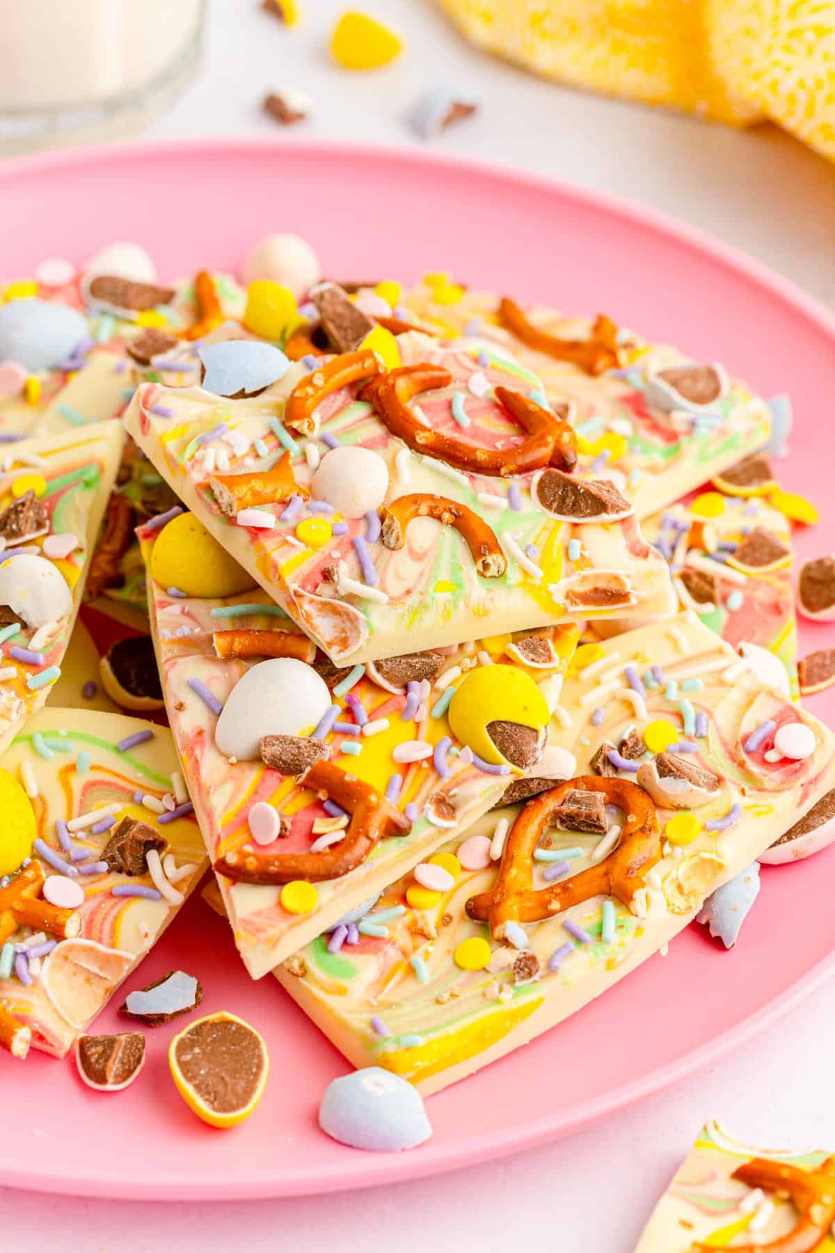 Easter bark with Cadbury mini eggs, pretzels, and sprinkles served on a pink plate.
