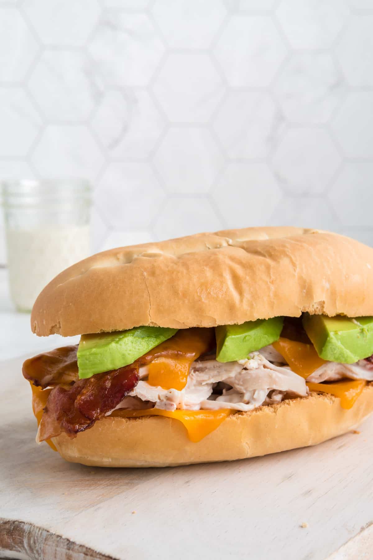 A chicken bacon ranch sandwich on a cuban roll with avocado.