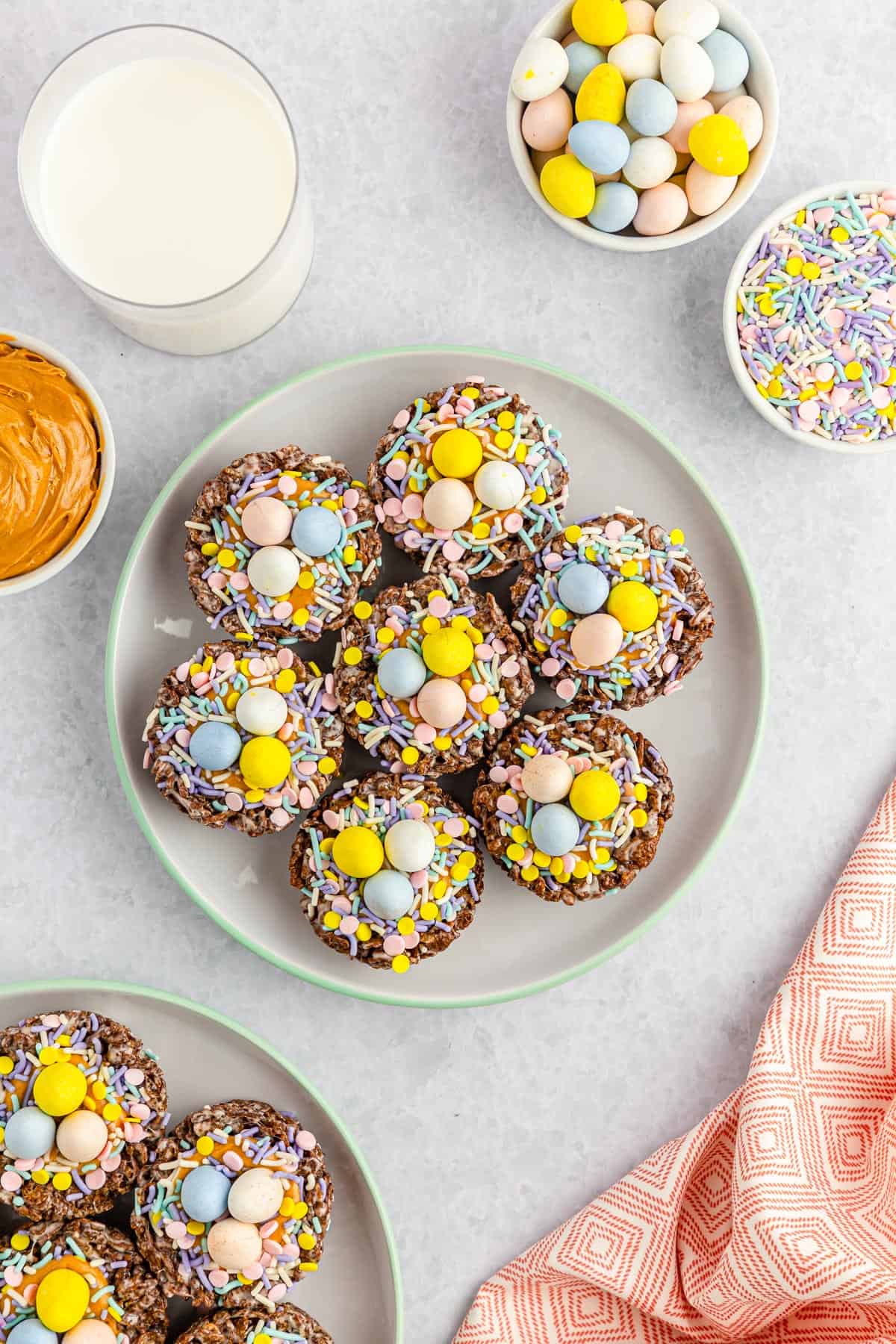 A plate full of peanut butter chocolate Easter nests with sprinkles and Cadbury mini eggs.