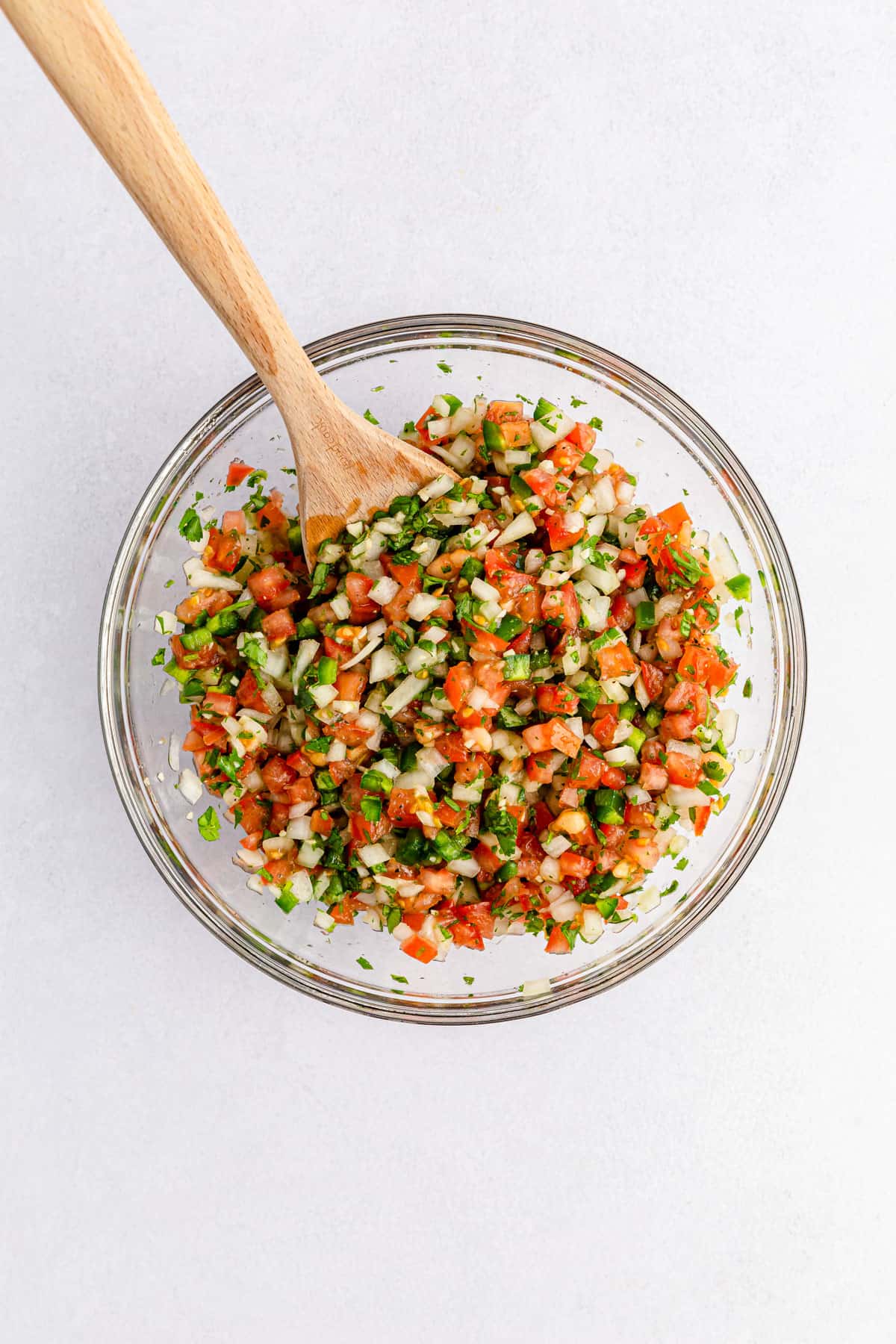 Classing pico de gallo ingredients mixed together in a glass bowl.