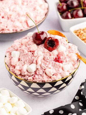 Classic cherry fluff salad in a black and white geometric bowl with a gold spoon.