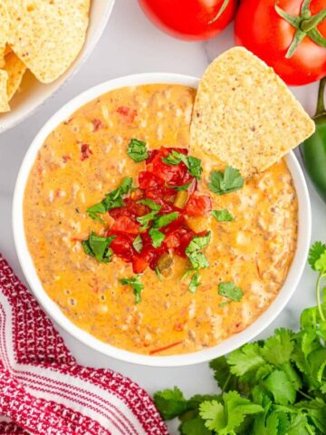 Sausage rotel dip served in a white bowl with a side or tortilla chips.