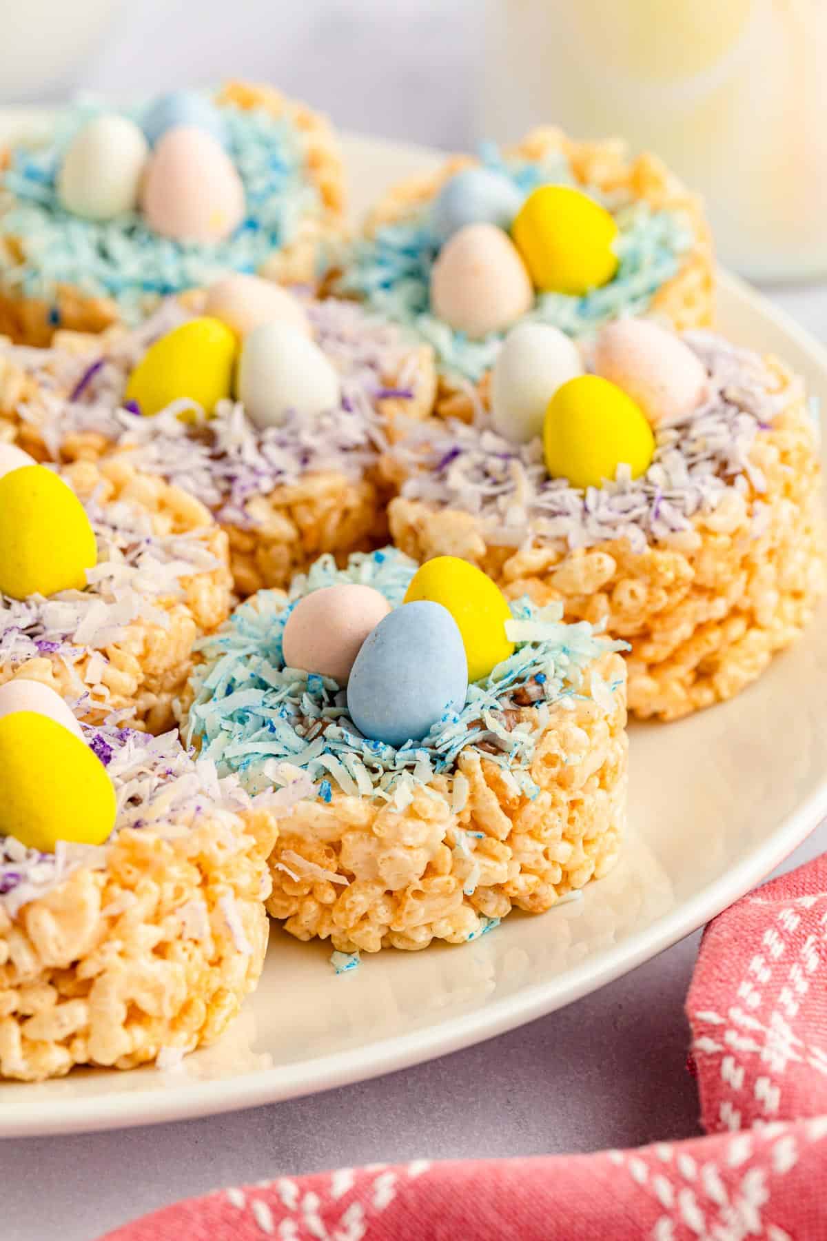Blue and purple mini egg rice krispie easter nests on a white plate.