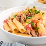 A close up shot of one pot spicy sausage pasta garnished with parsley.