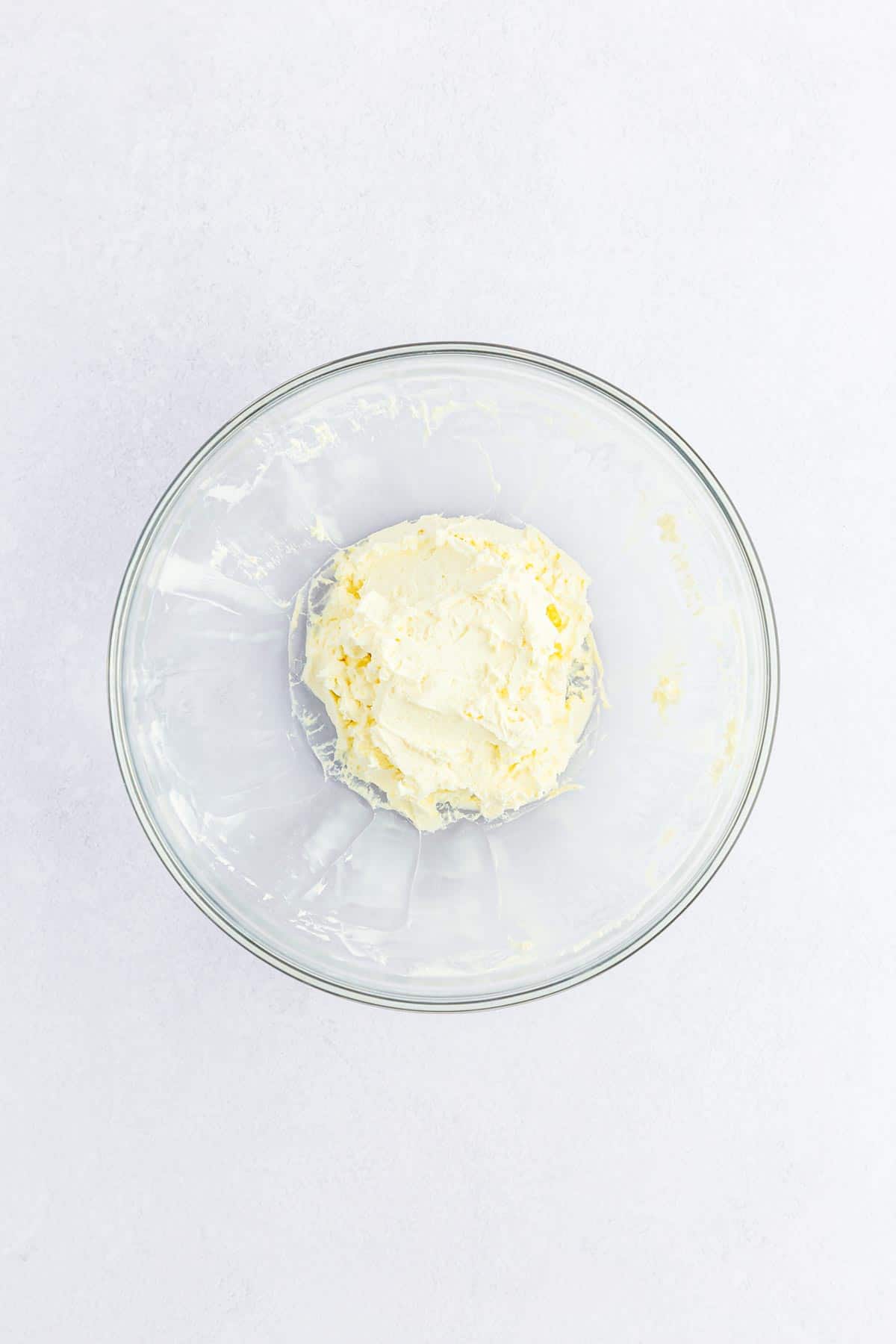 Cream cheese for carrot cake balls in a glass mixing bowl.