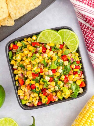 Chili corn salsa served in a grey bowl and garnished with lime slices.