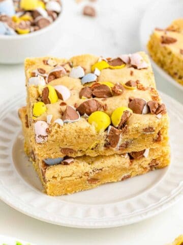 Two mini egg cookie bars stacked on a white plate.