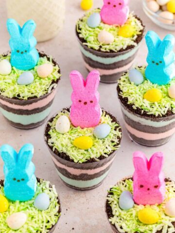 Peeps easter dirt cups with layers of pink and blue pudding and Oreo dirt.