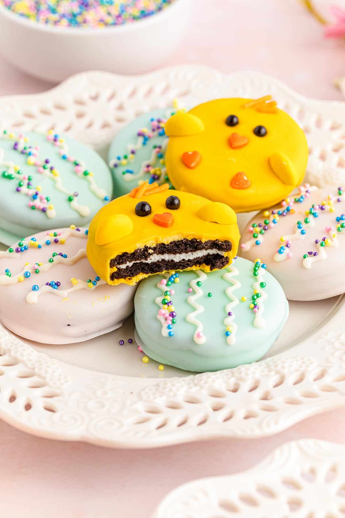 Chick and Easter egg oreos on a plate with a bite out of one of the chick oreos.