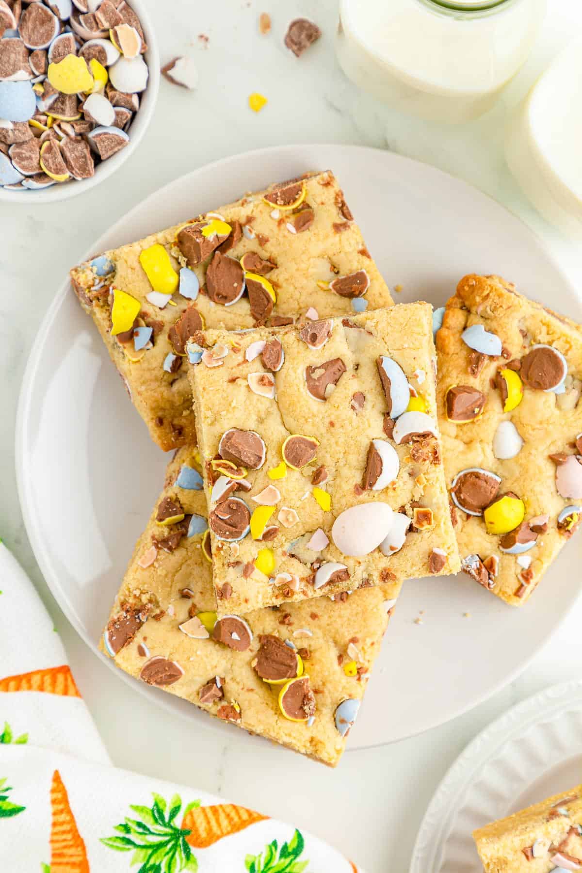Four mini egg cookie bars stacked on a white plate.