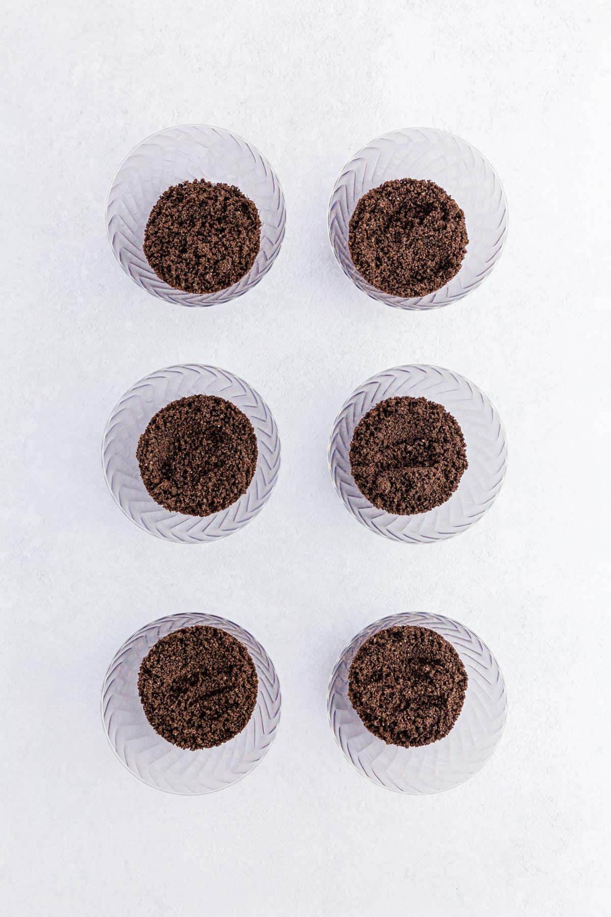 Adding Oreo dirt to plastic pudding cups.