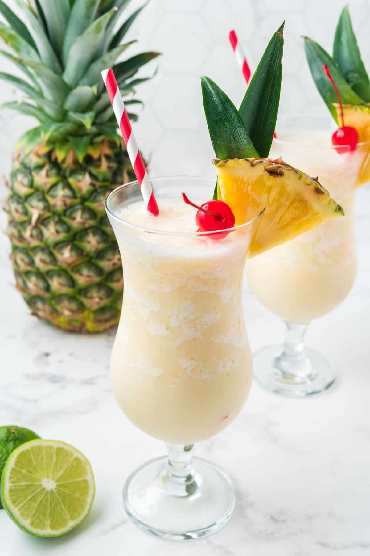 Two pina colada mocktails with lime and pineapple.