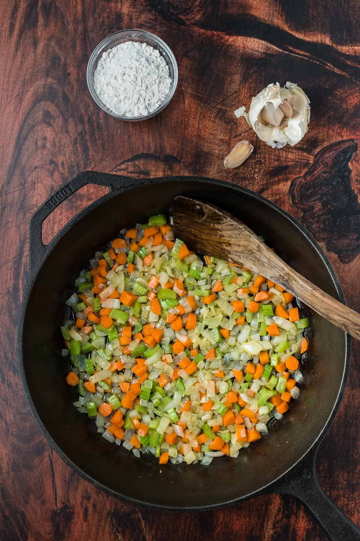Cooked vegetables for chicken pot pie in a cast iron pan.