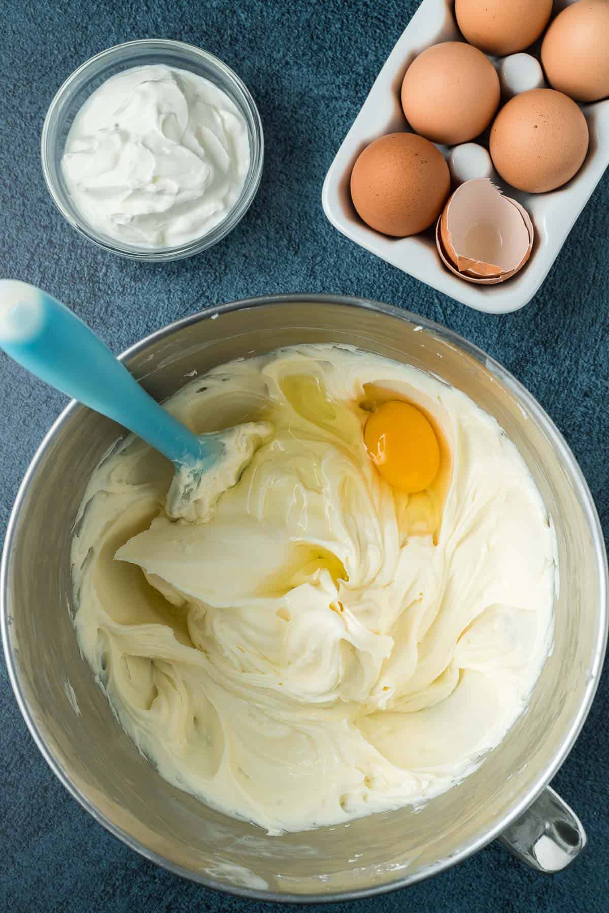 Adding eggs to chocolate orange cheesecake batter.