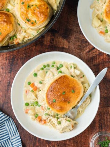 Chicken pot pie with biscuits served on a white plate.