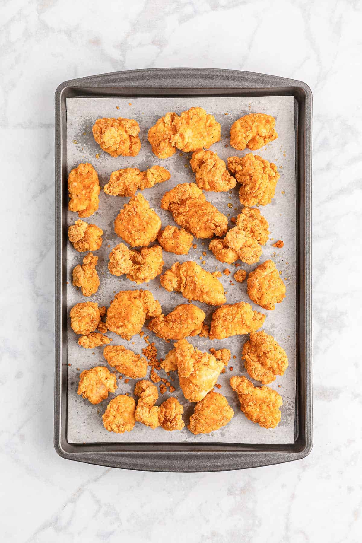 Cooked popcorn chicken on a baking tray.