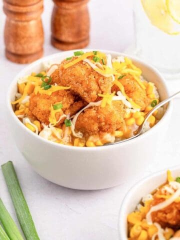 A homemade KFC famous bowl topped with cheddar cheese and green onions.