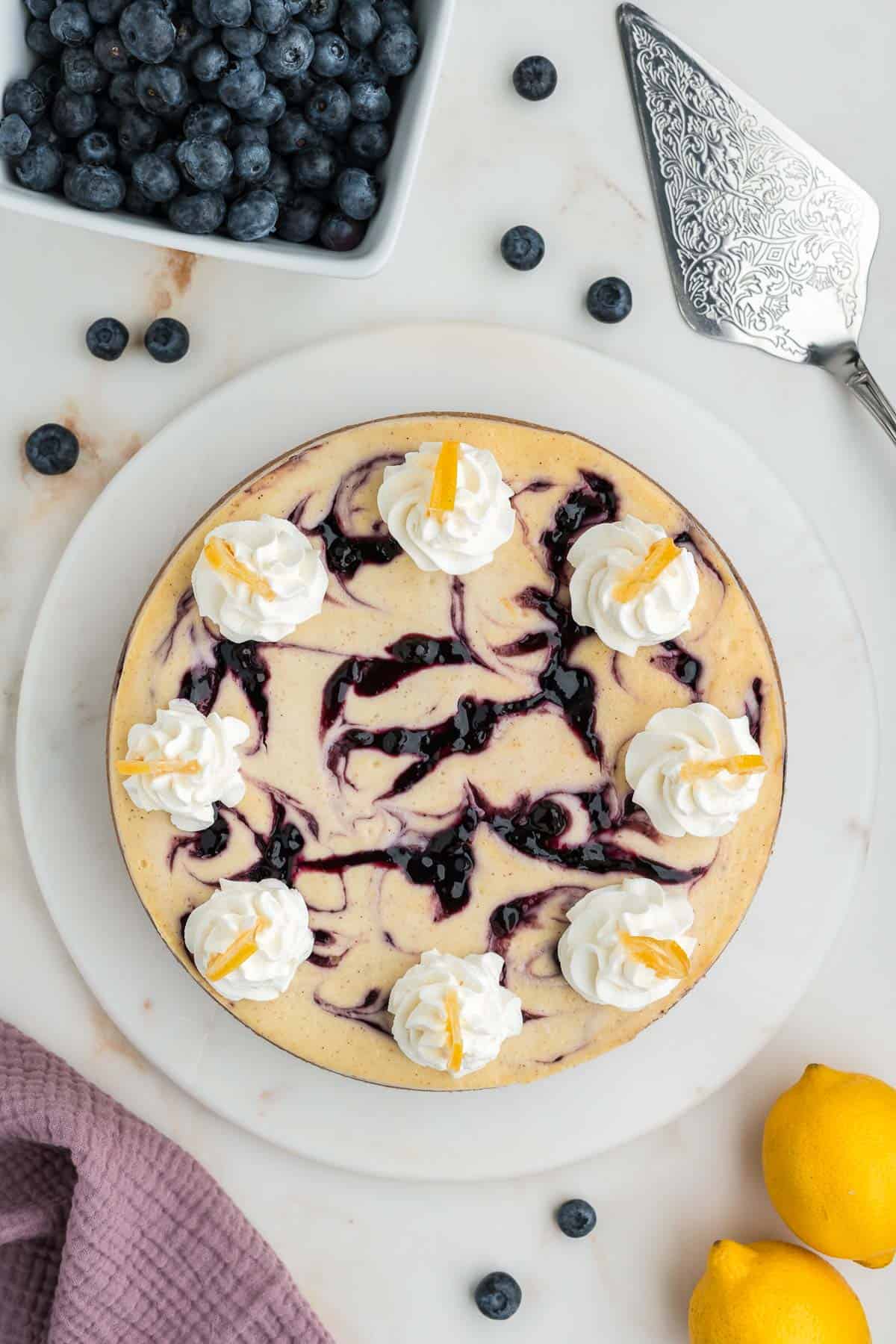 Overhead of lemon blueberry cheesecake on a marble platter.