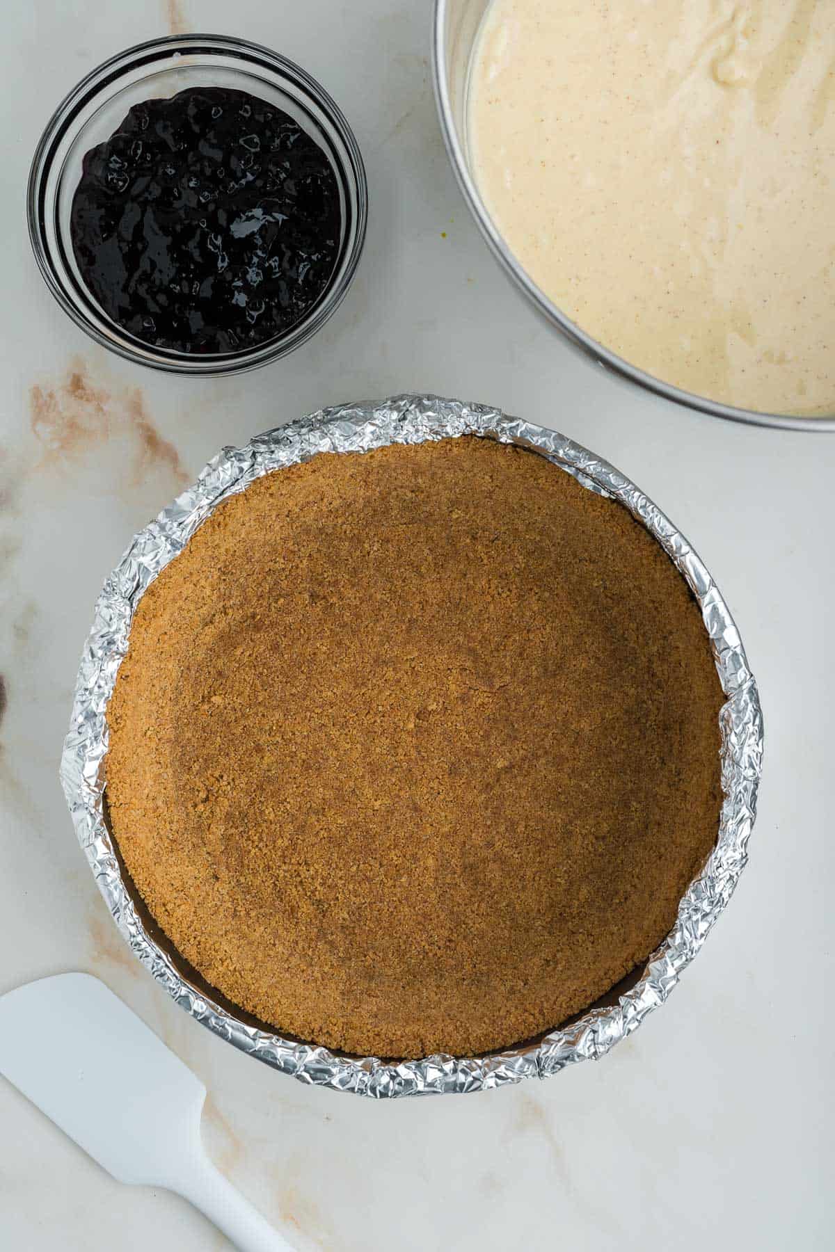 Graham cracker crust for cheesecake pressed into a springform pan.