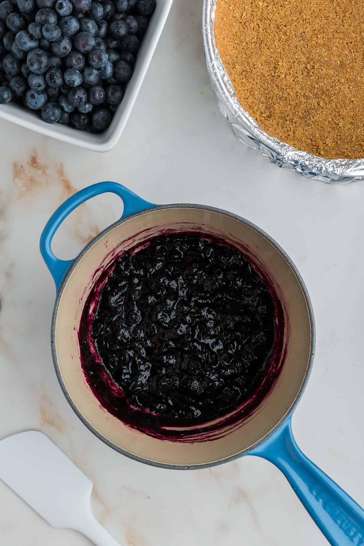 Finished blueberry compote in a blue saucepan.